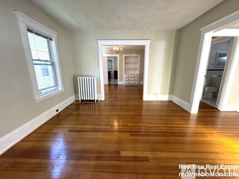 A spacious room with wooden floors and white walls.