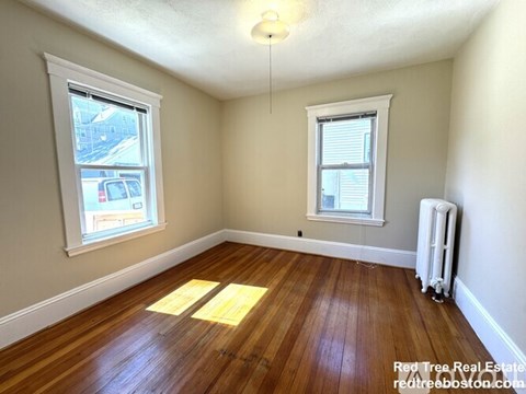 A room with wooden floors and two windows.