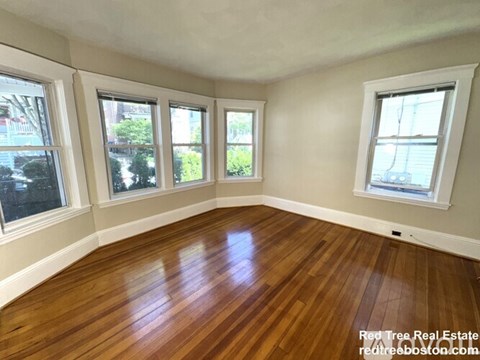 A room with wooden floors and three windows.