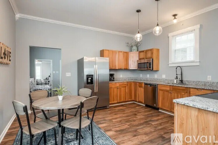 A kitchen with a table and chairs in the foreground and a refrigerator, microwave, and oven in the background.