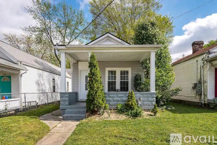 A white house with a porch and a green lawn in front.