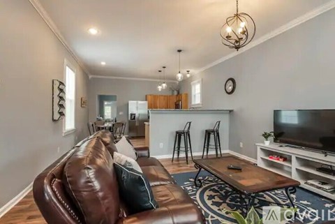 A living room with a brown leather couch and a television.