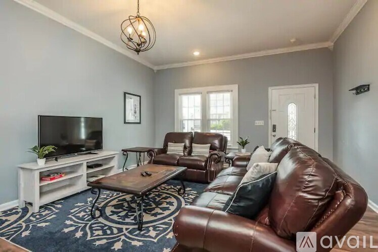 A living room with a brown leather couch and a television.