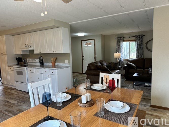 A dining table set with plates and glasses in a kitchen and living room.