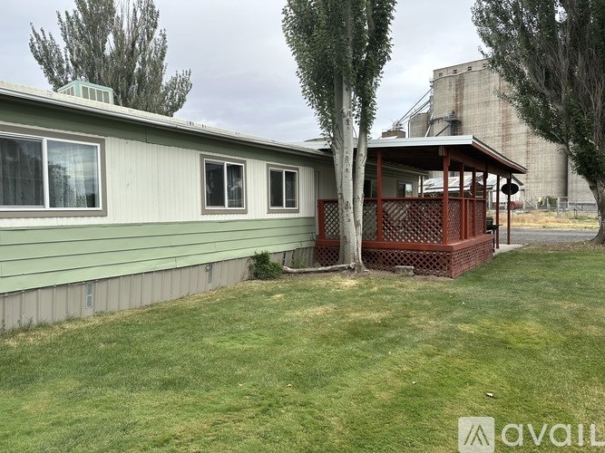 A house with a green siding and a red deck.