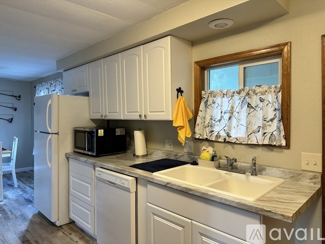 A kitchen with white cabinets and a black microwave.