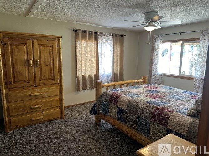 A bedroom with a bed, dresser, and window.