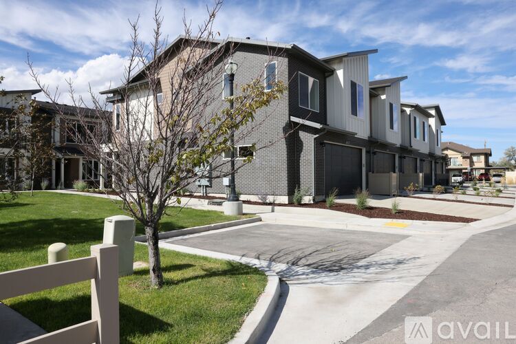 A row of modern houses with a tree and a white fence in the foreground.