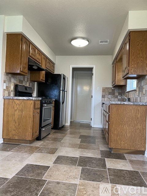 A kitchen with a black refrigerator and wooden cabinets.