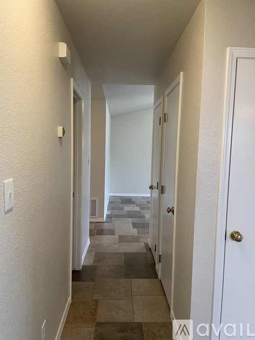 A hallway with a tiled floor and white walls.