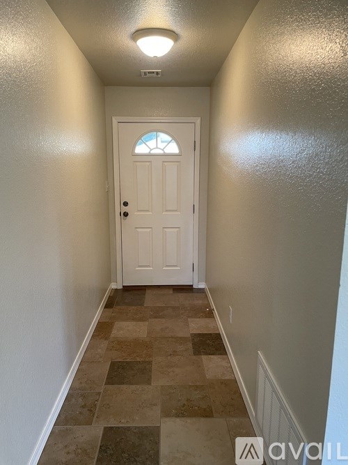 A hallway with a tiled floor and a white door.