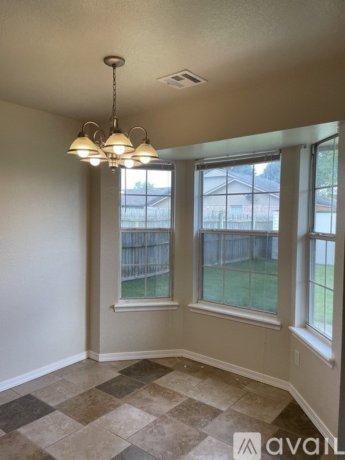 A room with a checkered floor and a window overlooking a fence.