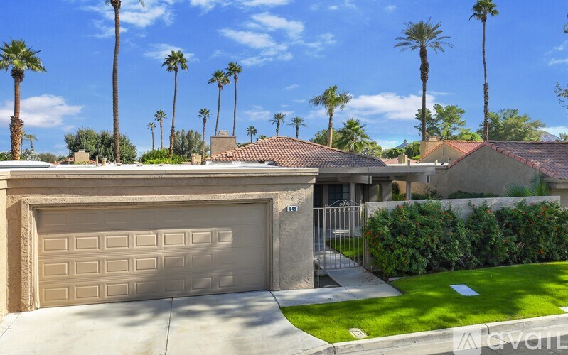 A house with a garage door and palm trees in the background.