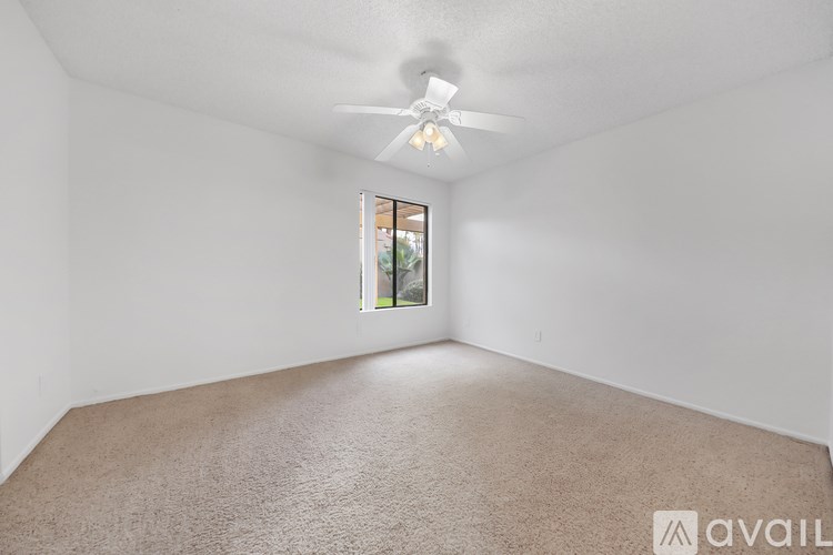 A room with a carpeted floor and a ceiling fan.