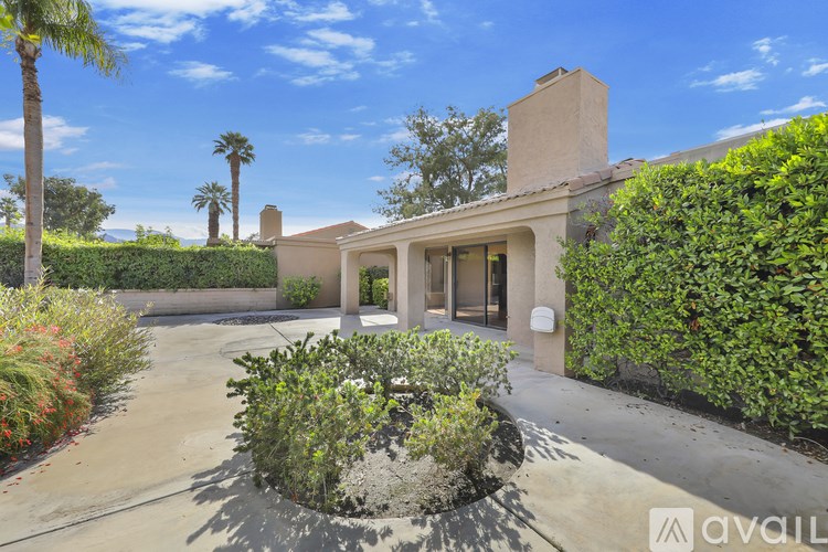 A house with a driveway and a hedge in front of it.