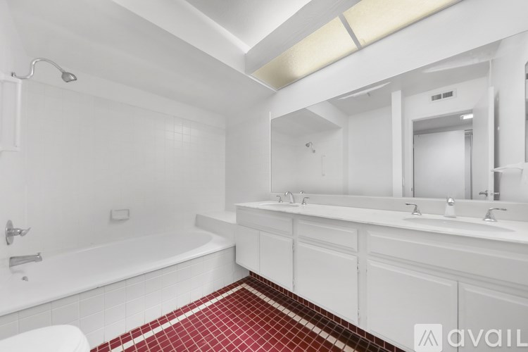 A white bathroom with a red tile floor.