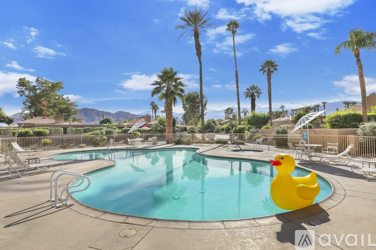 A yellow rubber duck is in a pool surrounded by palm trees.