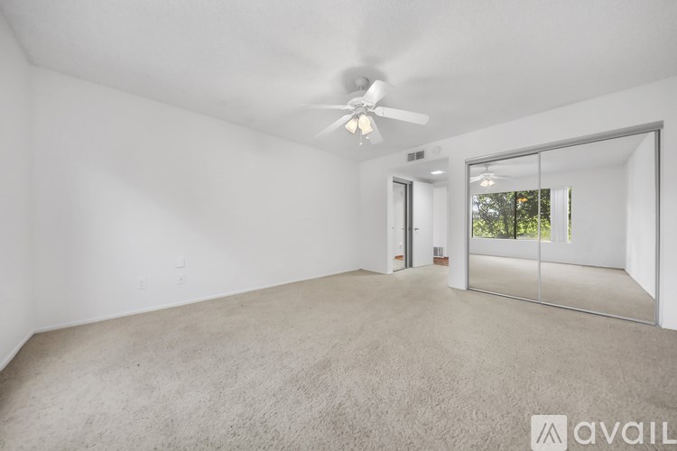 A spacious room with a ceiling fan and carpeted floor.