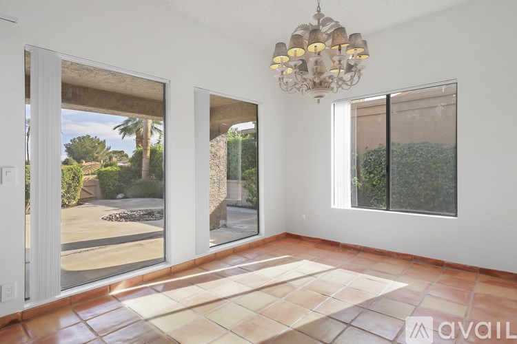 A room with a chandelier, tiled floor, and sliding glass doors.