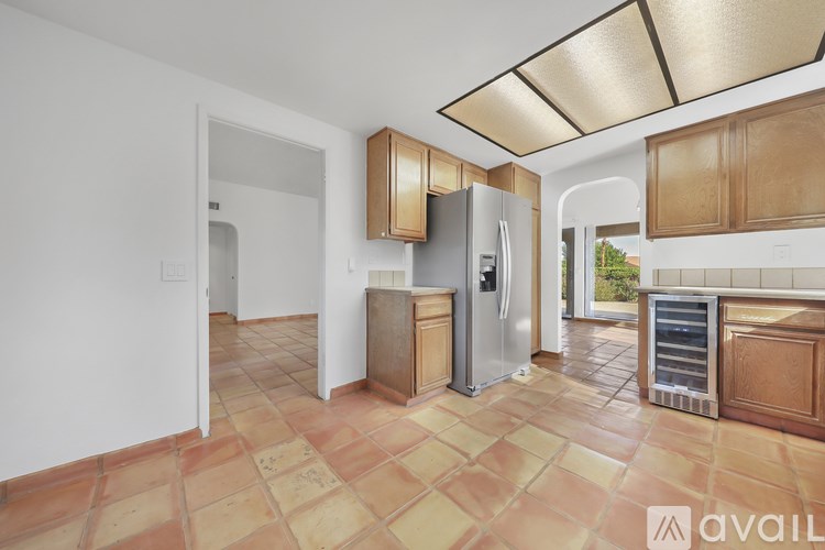A kitchen with a tile floor and a refrigerator.