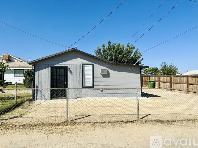 A grey house with a black door and a fence in front.