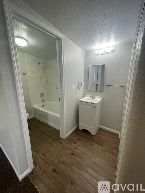 A bathroom with a white cabinet, sink, and a glass shower door.