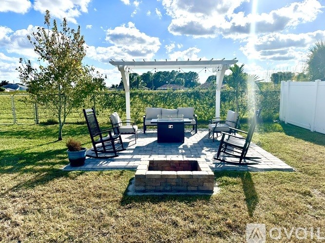 A patio with a fire pit and chairs under a pergola.