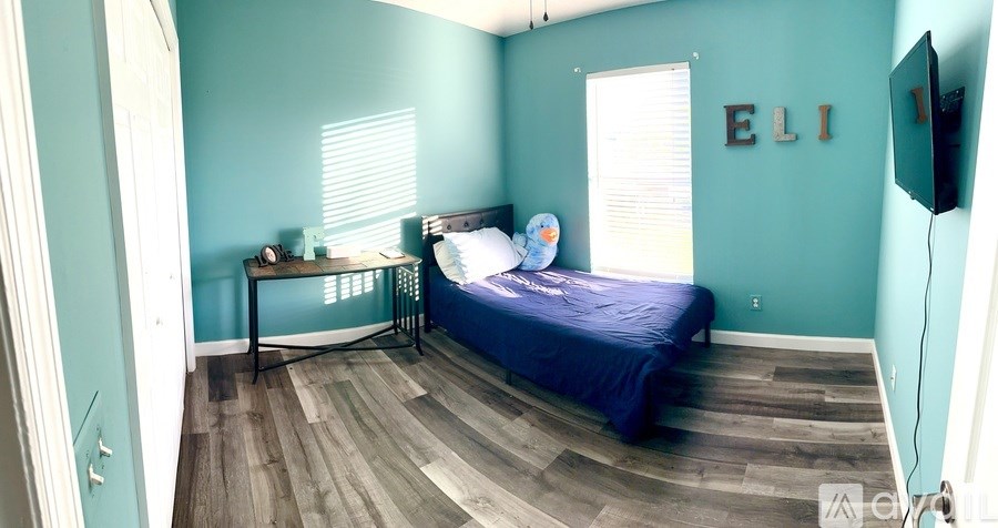 A bedroom with a bed, nightstand, and a window with blinds.