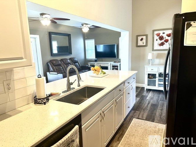 A kitchen with white cabinets and a black fridge.