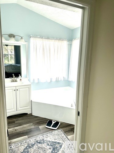 A white bathroom with a white tub and a white cabinet.
