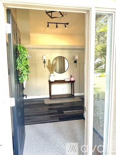 A bathroom with a round mirror and a potted plant on the door.