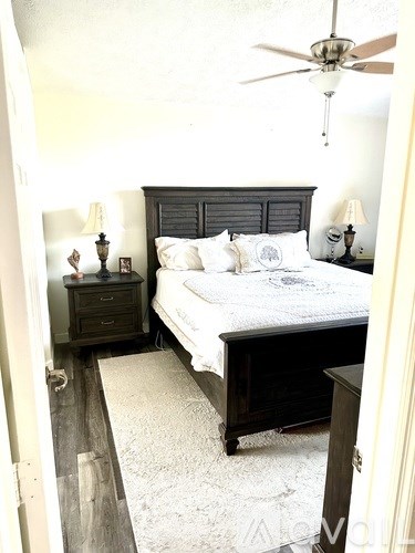 A bedroom with a bed, nightstand, and a ceiling fan.