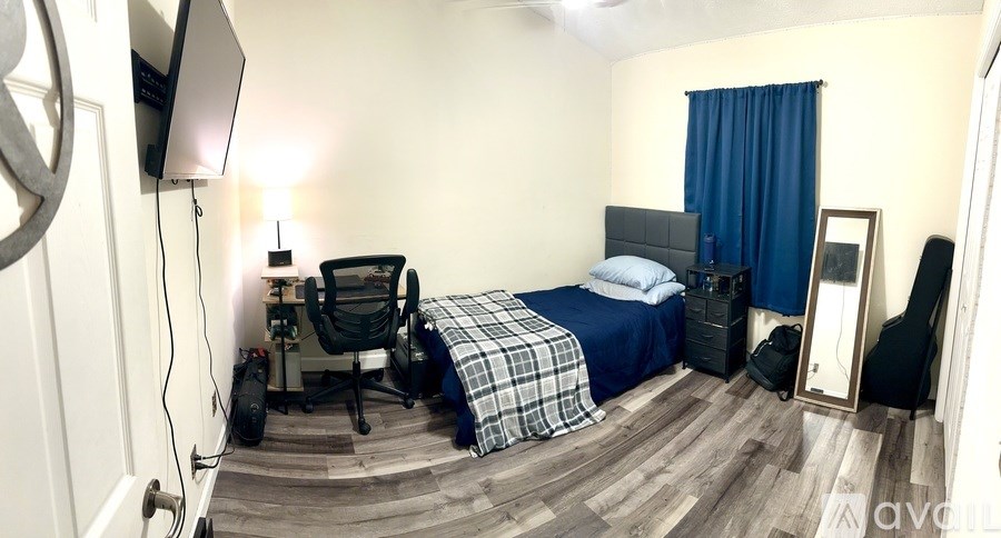 A bedroom with a bed, chair, and a TV mounted on the wall.