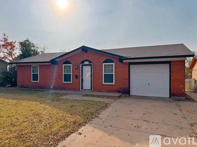 A red brick house with a white garage door and a driveway.
