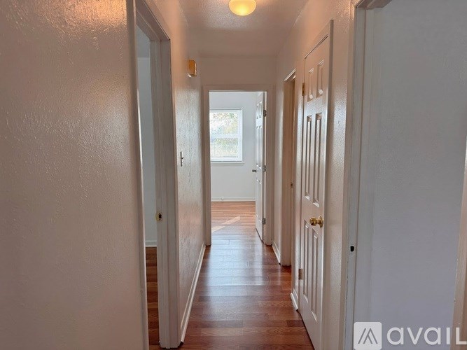 A long hallway with white doors and wooden floors.