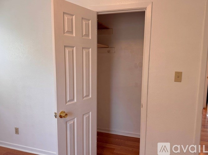 A white door with a gold handle is open to a small, empty room.