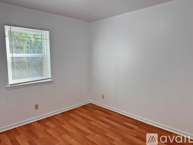 A room with wooden flooring and a window with blinds.