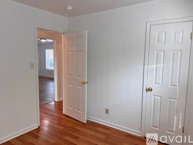 A room with a white door and a wooden floor.