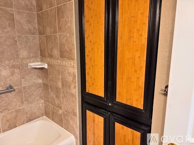 A white bathtub sits next to a brown door in a bathroom.