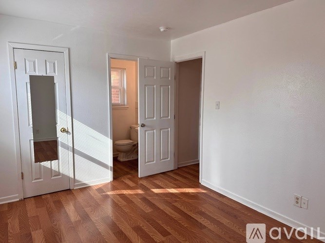 A room with a white door, a brown door, and a toilet in the middle.