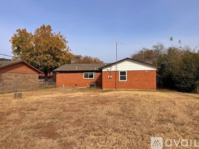 A house with a brown roof and a white door is surrounded by a field.