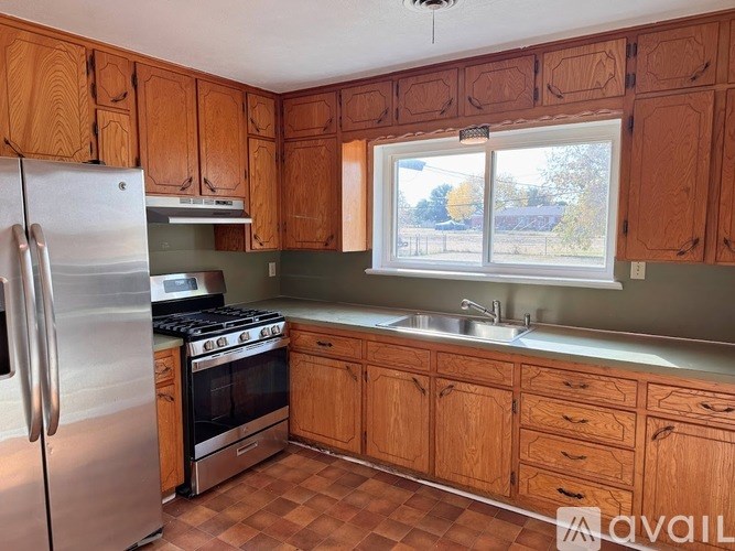 A kitchen with wooden cabinets and a stainless steel refrigerator.