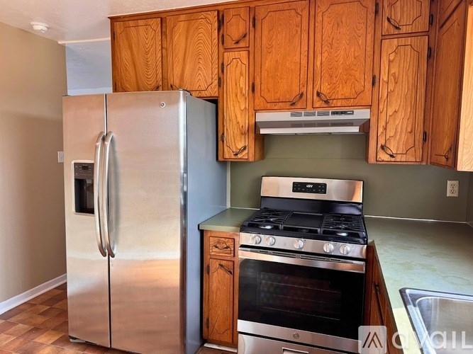 A kitchen with wooden cabinets and a stainless steel refrigerator.