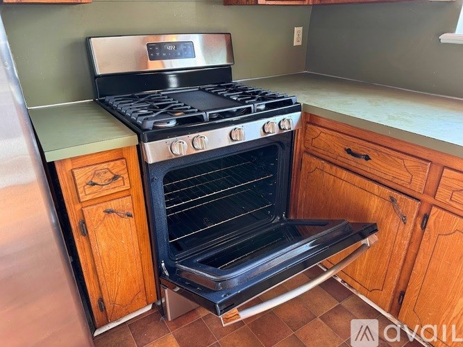 A black stove top oven with four burners and a digital clock on the front.