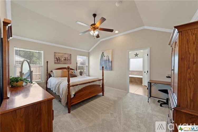 A bedroom with a bed, dresser, and a ceiling fan.