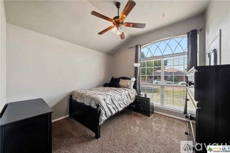 A bedroom with a bed, a ceiling fan, and a window with blinds.