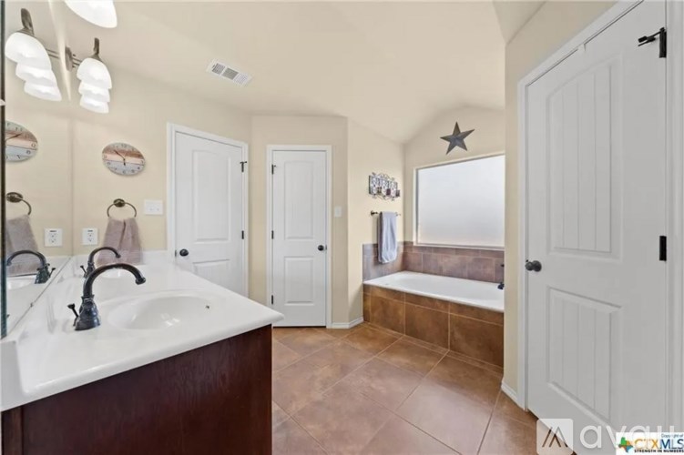 A bathroom with a white sink and brown countertop.