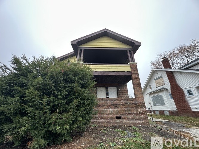 A house with a yellow front and a brick wall.