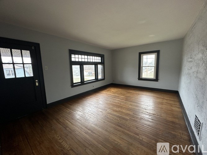 A room with wooden floors and three windows.