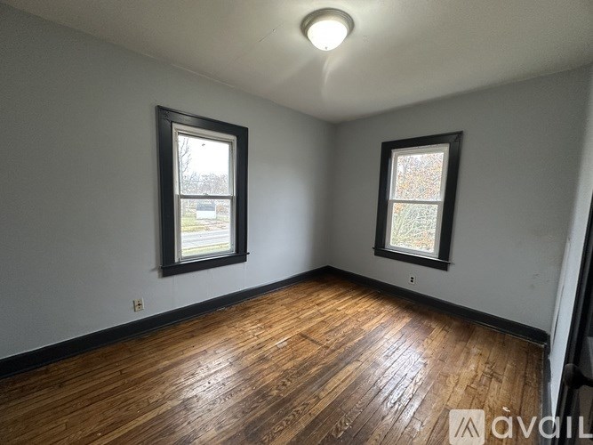 A room with wooden floors and two windows.
